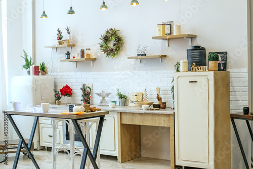 Fototapeta Naklejka Na Ścianę i Meble -  Bright kitchen interior with Christmas decor and Christmas wreath. Kitchenware.