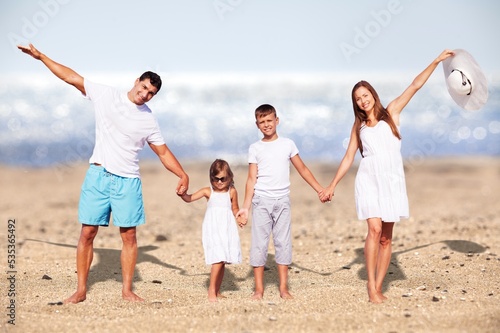 Vacation time. An excited afamily jumping on the beach with a beautiful ocean in the background.