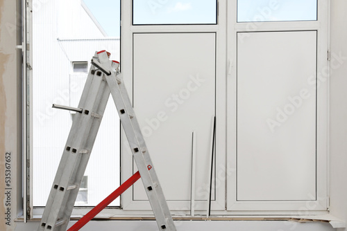 Folding ladder near open window indoors. Double glazing installation
