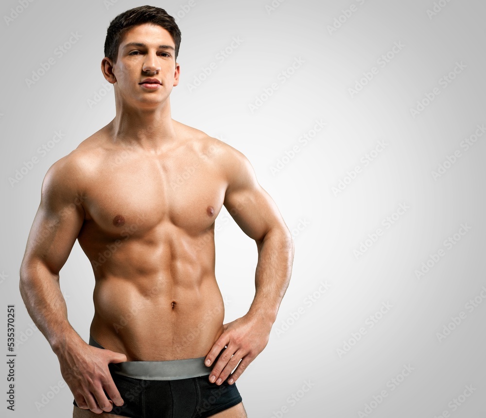 Handsome muscular young man posing against a grey background.