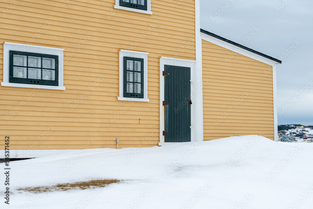A bright and cheerful yellow colored country style house with wood cape