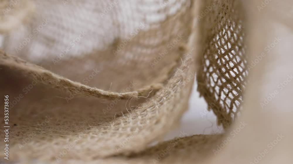 Sliding in front of loose hemp fabric on white background with selective focus creating background footage with texture and textile curves Sliding in front of loose hemp fabric on white background with selective focus creating background footage with texture and textile curves