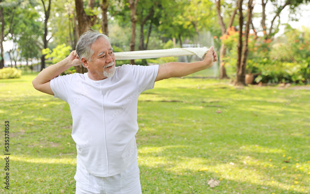 Asian senior man practice yoga excercise, tai chi tranining, stretching and meditation together with towel for relax healthy in park outdoor after retirement. Happy elderly outdoor lifestyle concept Asian senior man practice yoga excercise, tai chi tranining, stretching and meditation together with towel for relax healthy in park outdoor after retirement. Happy elderly outdoor lifestyle concept