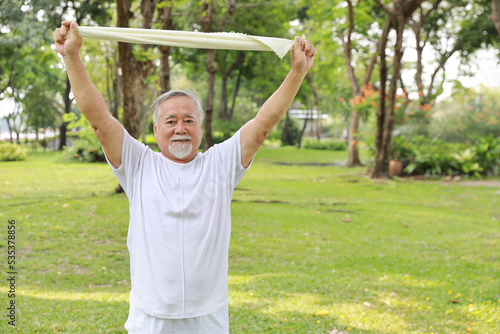 Asian senior man practice yoga excercise, tai chi tranining, stretching and meditation together with towel for relax healthy in park outdoor after retirement. Happy elderly outdoor lifestyle concept © feeling lucky