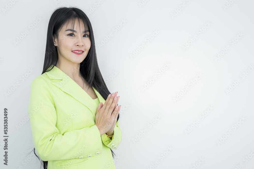 Asian working Thai business woman wearing green pastel suit made hello gesturing Sawasdee and smiling, Thai culture friendly greeting, Sawasdee symbol from Thailand greeting culture identity. Asian working Thai business woman wearing green pastel suit made hello gesturing Sawasdee and smiling, Thai culture friendly greeting, Sawasdee symbol from Thailand greeting culture identity.
