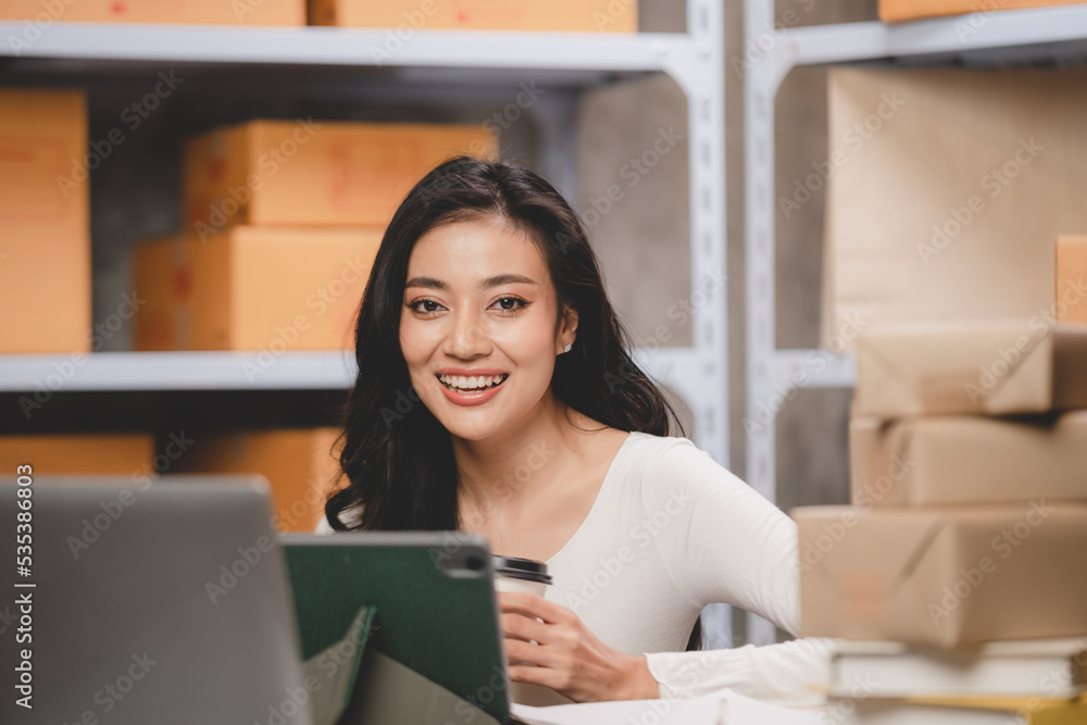 online shopping concept, happy young Asian business owner woman prepare parcel box and check orders of product for deliver to customer on laptop computer at home, e-business marketing on cyberspace online shopping concept, happy young Asian business owner woman prepare parcel box and check orders of product for deliver to customer on laptop computer at home, e-business marketing on cyberspace