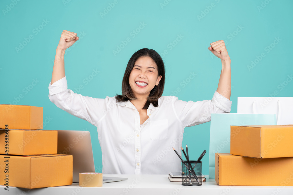 Successful Asian businesswoman wearing white shirt is gesturing winner isolated on green background. with brown cardboard box Successful Asian businesswoman wearing white shirt is gesturing winner isolated on green background. with brown cardboard box