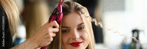Fotografie Master woman hairdresser curls hair of girl in beauty salon