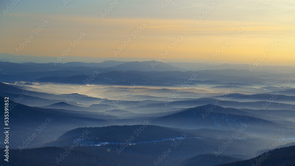 Colorful mountain hills with tonal perspective at winter evening at sunset. Abstract panoramic landscape in Gornaya Shoria, Sheregesh ski resort in Russia Foggy Mountains nature background