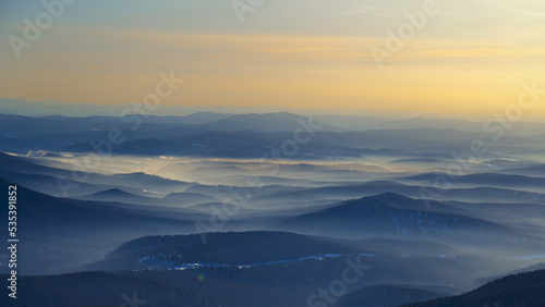 Colorful mountain hills with tonal perspective at winter evening at sunset. Abstract panoramic landscape in Gornaya Shoria, Sheregesh ski resort in Russia Foggy Mountains nature background © yrabota