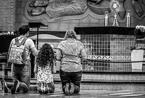 Grayscale photo of woman and man and girl praying at the alter photo