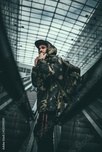 Man in camouflage jacket standing on escalator photo
