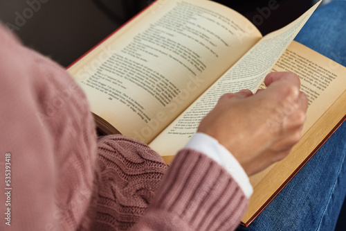 Person in pink sweater holding book page photo