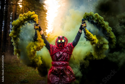 Person in red costume standing in the forest in the middle of colored smoke photo