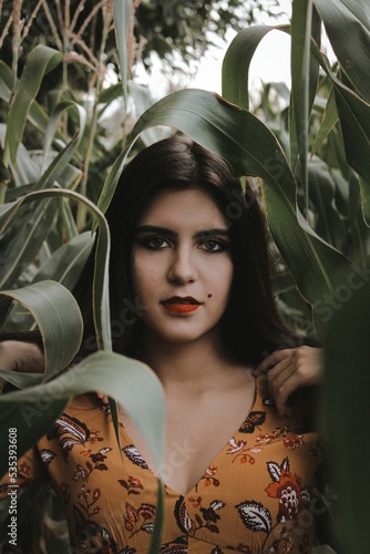 Portrait of woman in floral outfit between green plants photo