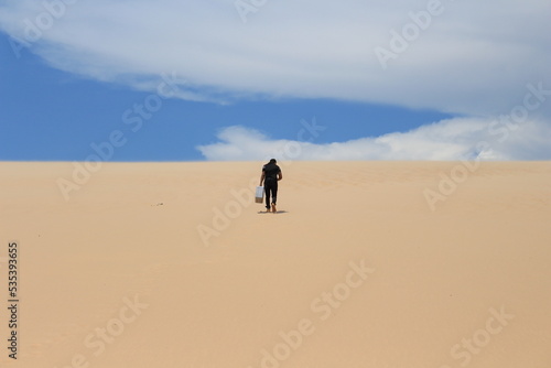 Young man walking on the sand and looking for a sign - LOMAS DE ARENA SANTA CRUZ BOLIVIA