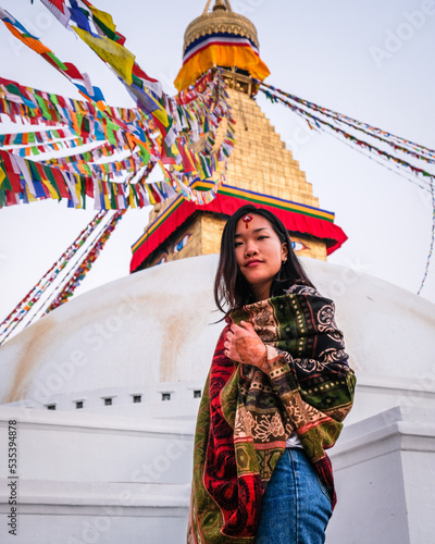 Woman in tribal outfit standing beside tribal decoration on top of white concrete building