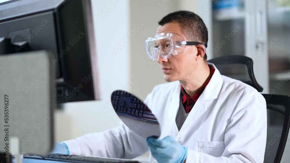 midage chinese technician researching semiconductor wafer in library midage chinese technician researching semiconductor wafer in library
