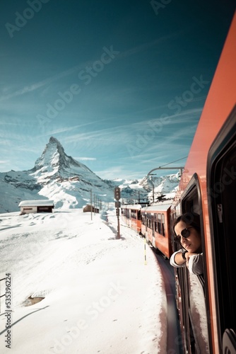 Young woman looking out from red train on snow covered field photo