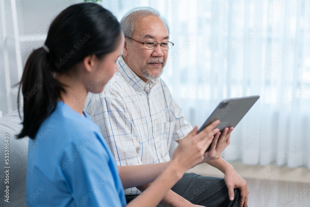 Asian nurse showing health checkup report to grandfather and giving advice. medical assisted living visit senior patient at home. Home nursing and healthcare caregiver concept Asian nurse showing health checkup report to grandfather and giving advice. medical assisted living visit senior patient at home. Home nursing and healthcare caregiver concept