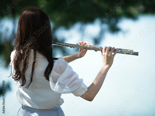 外でフルートを吹く女性の後ろ姿