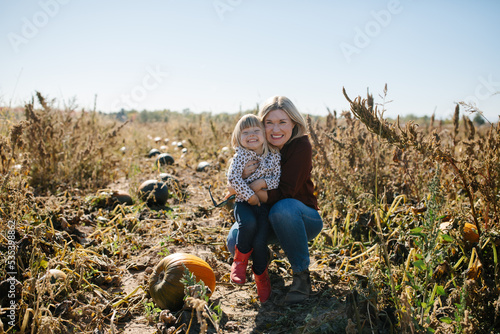 mother and daughter hugging and smiling together in a pumpkin patch