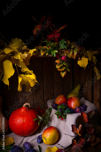 Various fruits in a wooden box with autumn leaves