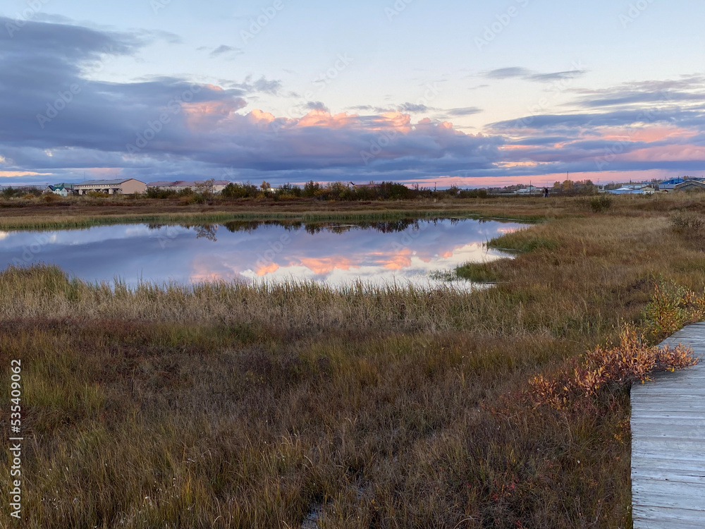 Fototapeta premium Walking on the boardwalk in Bethel with beautiful colors in the sky, on the water and on the tundra (September 2022)