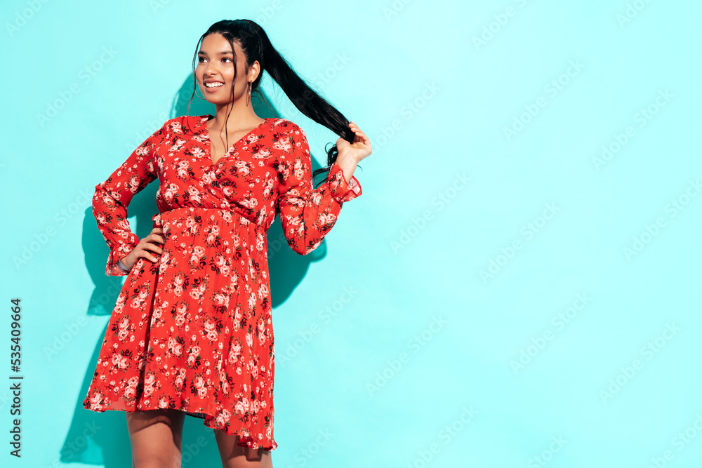 Young beautiful smiling female in trendy summer red dress clothes. carefree woman posing near blue wall in studio. Positive model having fun and going crazy. Cheerful and happy Young beautiful smiling female in trendy summer red dress clothes. carefree woman posing near blue wall in studio. Positive model having fun and going crazy. Cheerful and happy