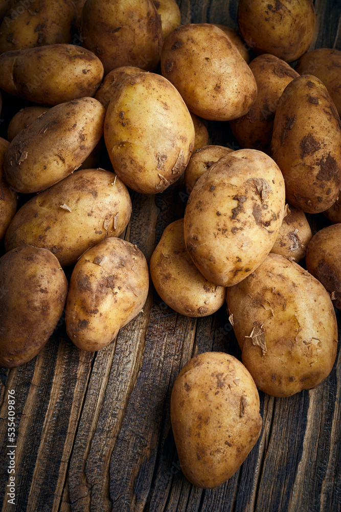 Raw ripe potatoes on wooden background Raw ripe potatoes on wooden background