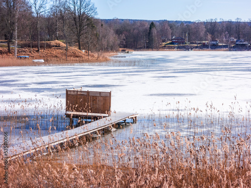 Wooden jetty by a lake with ice