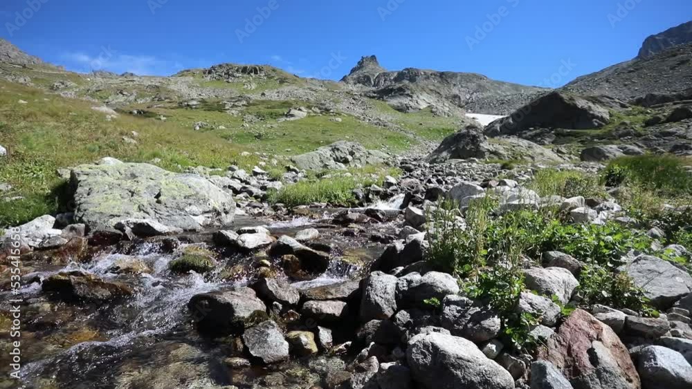 Scenic landscape with a fast mountain river flowing between rocky stones. The waterfall falling from top of mount. Snow and glaciers on mountain slopes. Caucasus Scenic landscape with a fast mountain river flowing between rocky stones. The waterfall falling from top of mount. Snow and glaciers on mountain slopes. Caucasus