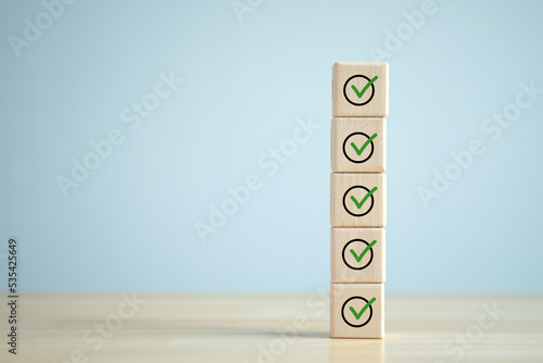 Checklist, Task list, Survey and assessment. Quality Control. Goals achievement and business success. Green check mark icon on wooden blocks.