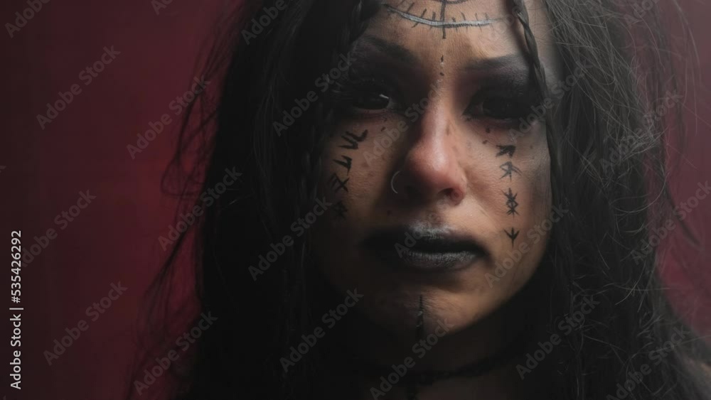 Portrait of a witch girl with black eyes on a red background in the smoke. Portrait of a witch girl with black eyes on a red background in the smoke.