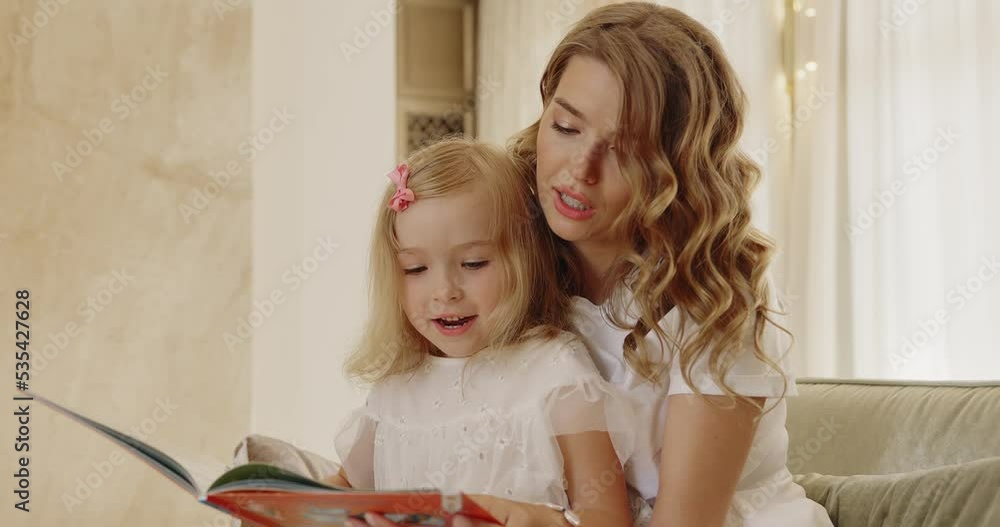 Mother reading interesting book to her little blonde daughter Mother reading interesting book to her little blonde daughter