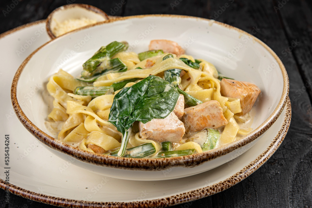 delicious pasta with cheese, salmon, greens, sauce in a restaurant
