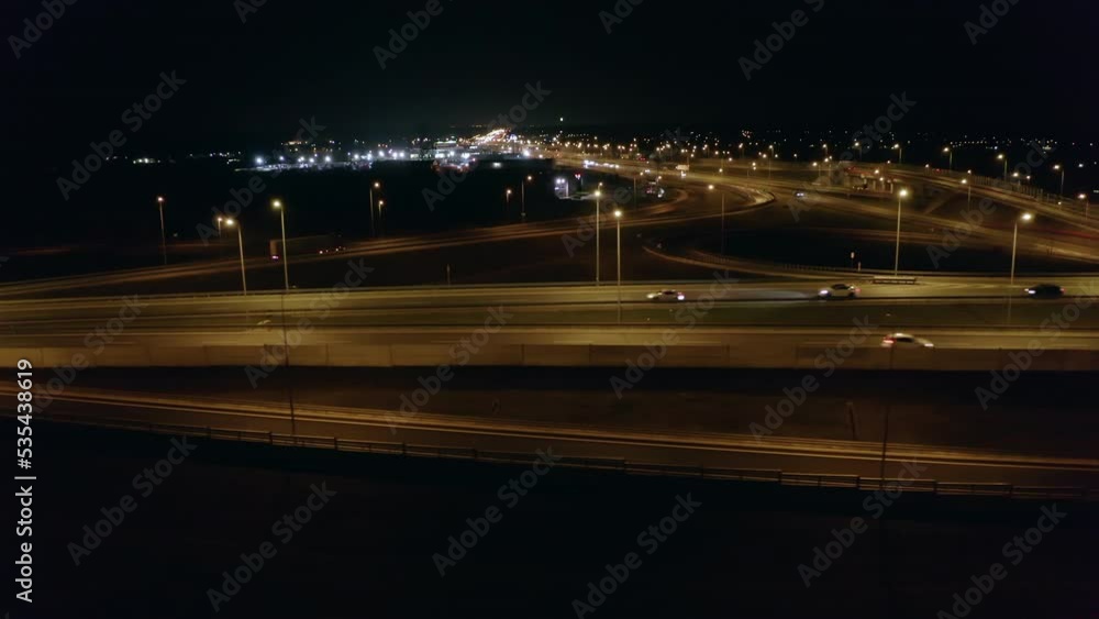 Drone shot of a multi-lane freeway with bridges and viaducts at night with cars and trucks. Aerial view of a large freeway and interchange in the suburbs of Warsaw, Poland. Drone shot of a multi-lane freeway with bridges and viaducts at night with cars and trucks. Aerial view of a large freeway and interchange in the suburbs of Warsaw, Poland.