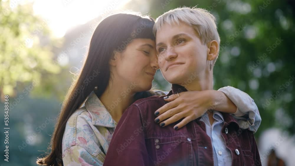 Lesbian family standing, one partner hugging her girlfriend. Lgbt woman, showing love to each