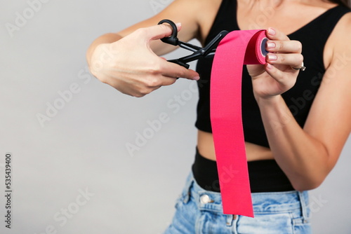 woman holds kinesiology tape and scissors close up. 