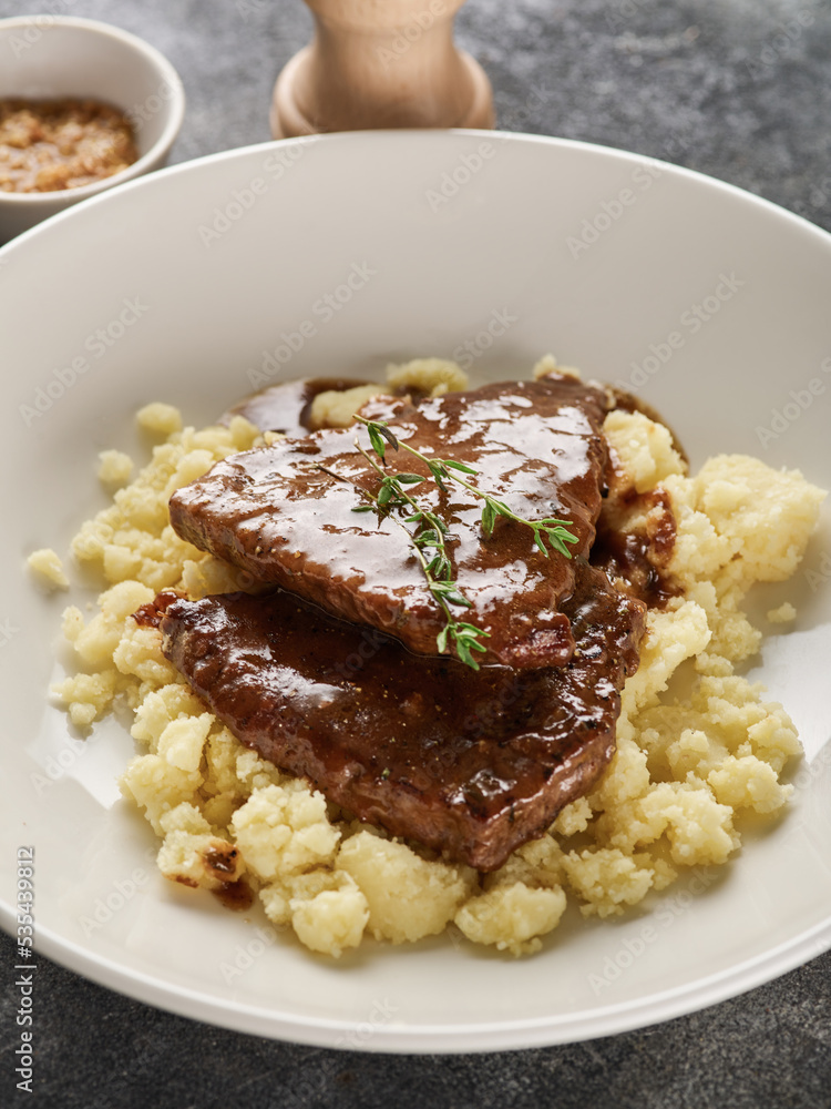 Close up view of sliced roasted beef with mashed potato on plate over grey background Close up view of sliced roasted beef with mashed potato on plate over grey background