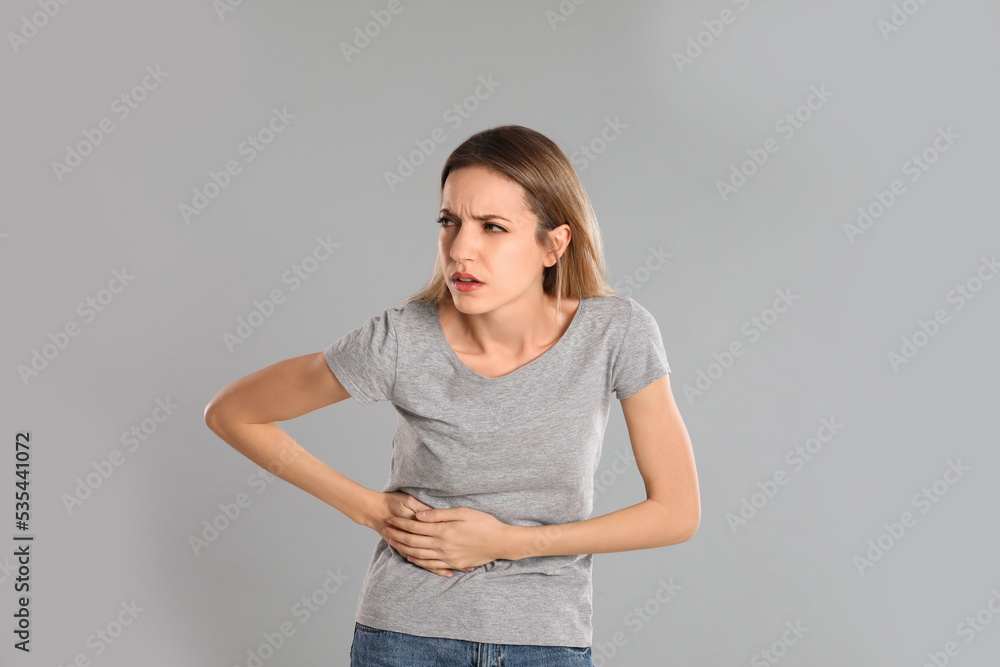 Young woman suffering from liver pain on grey background Young woman suffering from liver pain on grey background