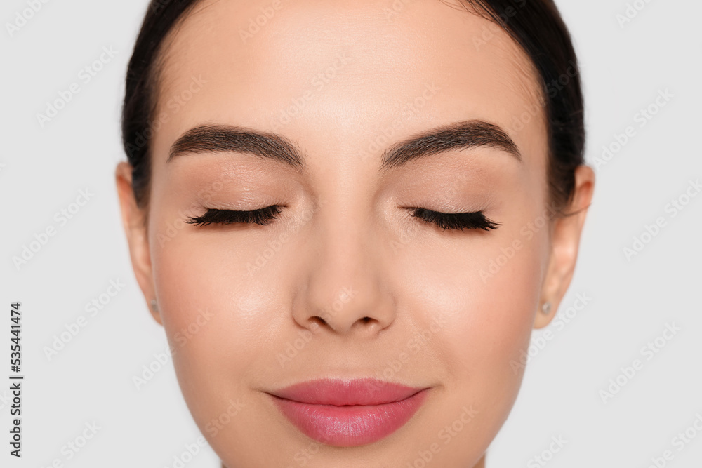 Beautiful young woman with long eyelashes on light background, closeup Beautiful young woman with long eyelashes on light background, closeup