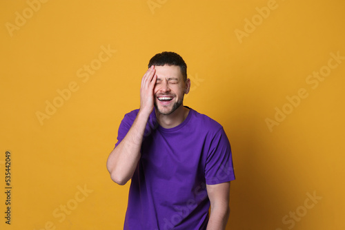 Handsome man laughing on yellow background. Funny joke © New Africa