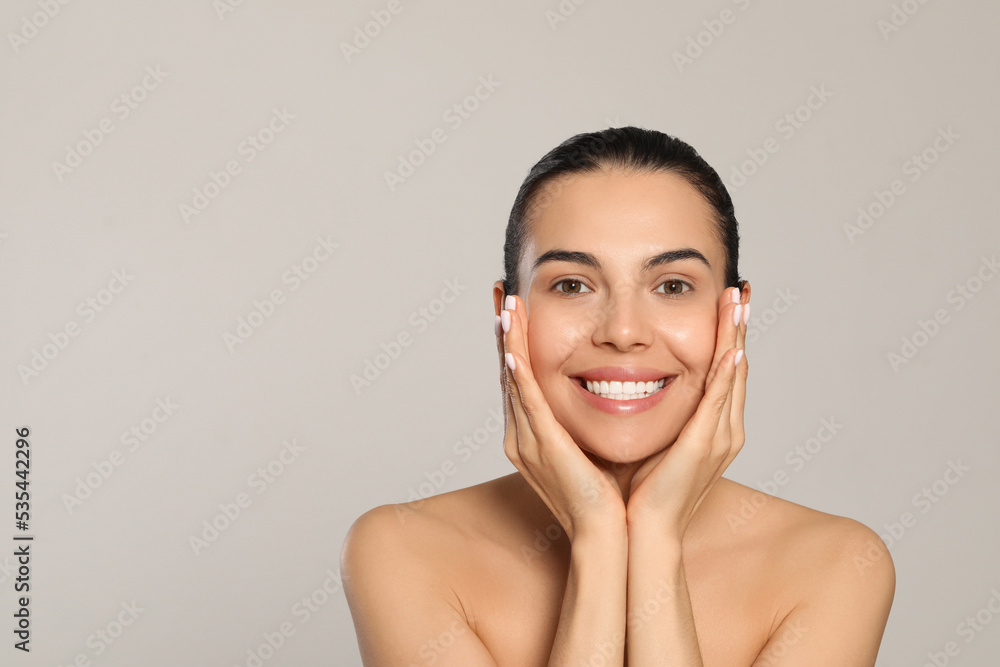 Beautiful young woman with perfect skin on light grey background, space for text Beautiful young woman with perfect skin on light grey background, space for text