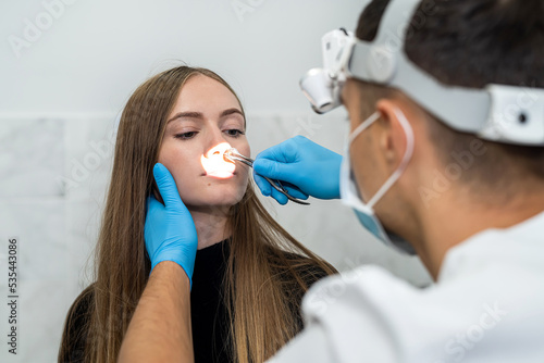 male otolaryngologist examines the nose of a female patient before a nasal endoscopy procedure photo