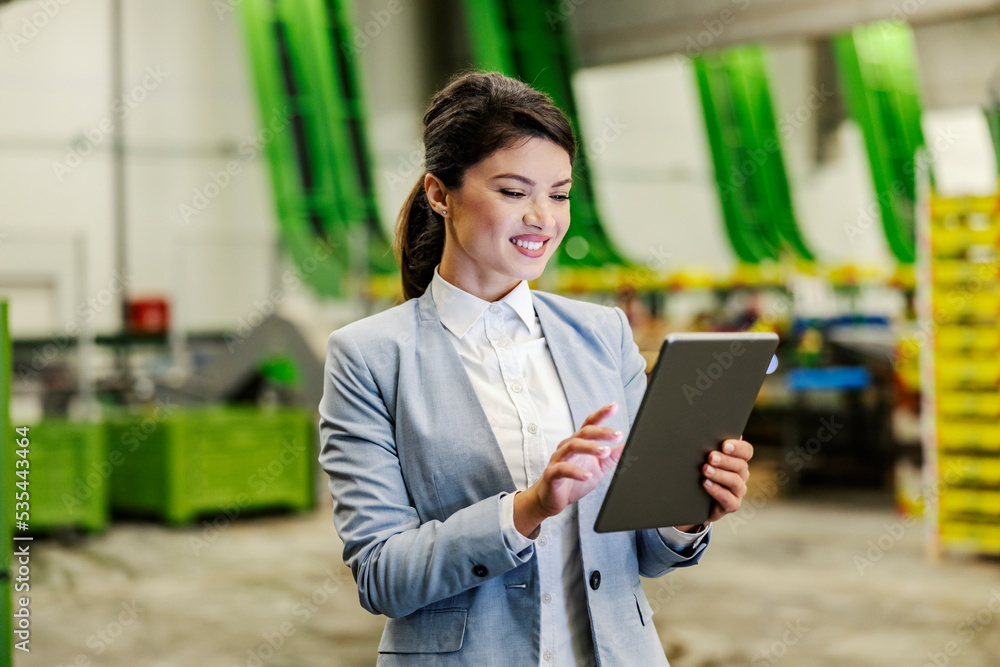 A businesswoman scrolling on tablet in fruit production warehouse. A businesswoman scrolling on tablet in fruit production warehouse.