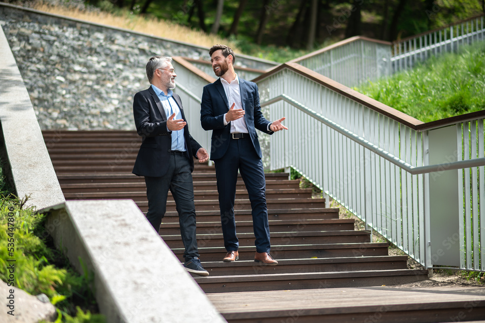 Two businessmen walking down the stairs and talking