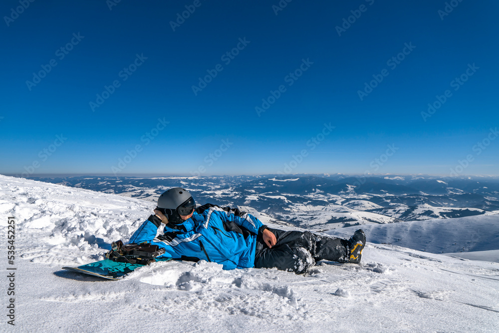 Snowboarder with snowboard relax on mountain top. Winter freeride snowboarding