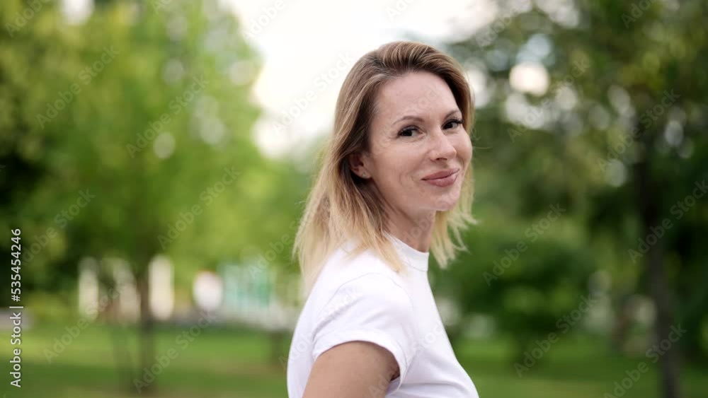 portrait of beautiful middle-aged blonde woman in park in summer, medium shot in movement portrait of beautiful middle-aged blonde woman in park in summer, medium shot in movement
