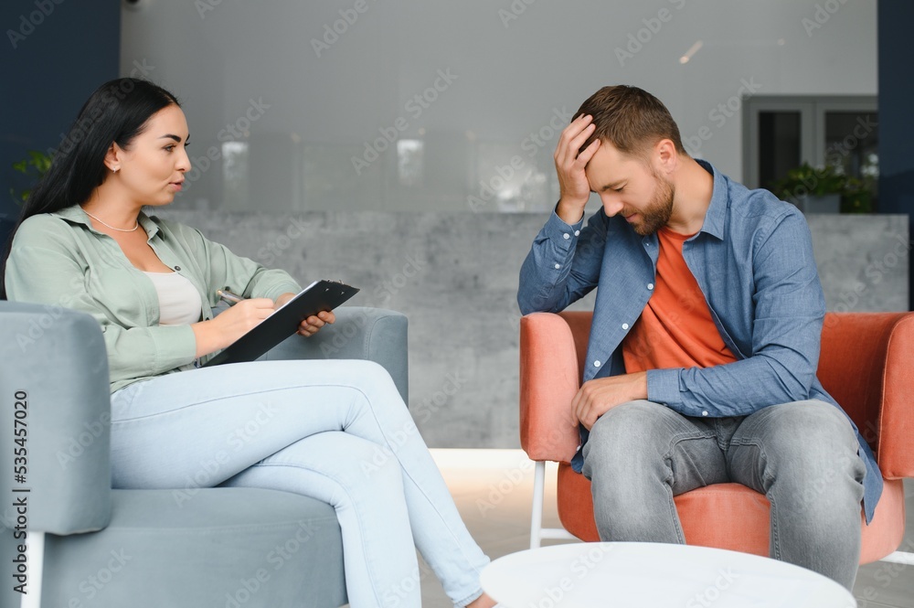 psychology, mental therapy and people concept - woman psychologist talking to sad young man patient at psychotherapy session.